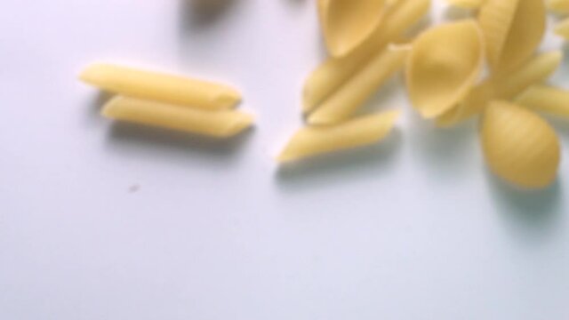 Super slow motion of flying uncooked italian pasta on white background.