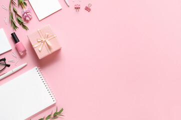 Workplace with notepad, pen, gift and other accessories on pink background