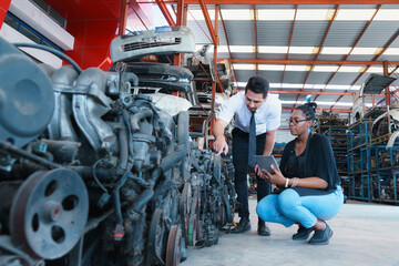 Diversity of two people, caucasian business manager asking detail of engine from African worker woman in factory-warehouse