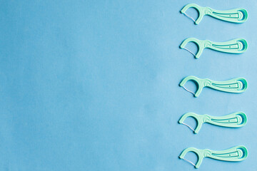 Dental floss in the row on blue background. Oral hygiene and helthy teeth and interdental space...