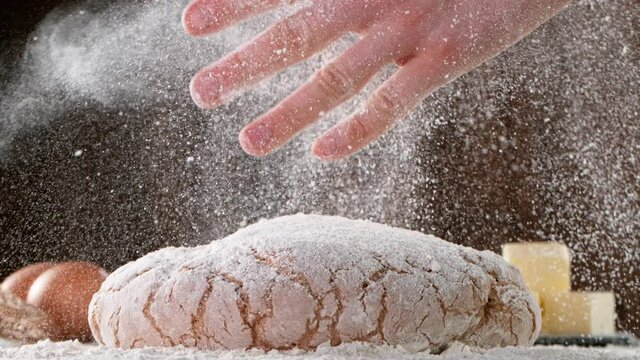 Close up shot of man hands kneading bread dough at the wooden table.