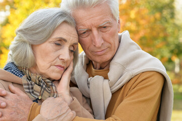 Sad senior couple in autumn park