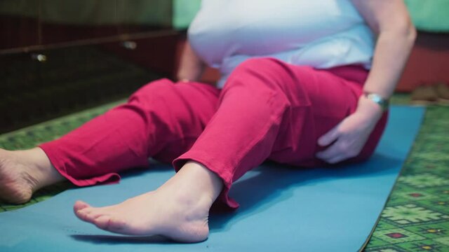 Seniour woman does tibetian gymnastics as morning exercises. Isolation of old people at home during pandemic.