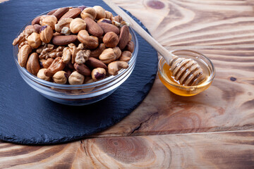 Assorted nuts in glass bowl with honey bowl and honey dipper