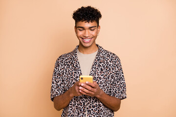 Portrait of positive young dark skin guy beaming smile typing blog post comment isolate don beige color background