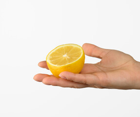 female hand holds half a yellow lemon on a white background