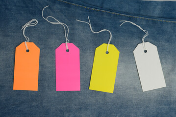 blank rectangular cardboard colored tags on blue jeans background