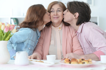 family of three spending time together at dinner table with cookies and tea
