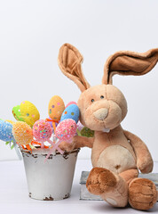 teddy bunny sitting on a white background and decorative colorful easter eggs