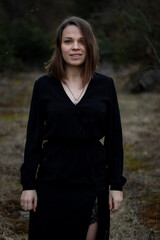 young brunette woman with short hair in a black dress on the nature