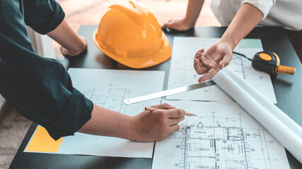 Meeting of engineers and architects in building planning, Consulting and brainstorming experts in architectural planning using blueprints, tape measure, rulers, laptop in designing buildings. - obrazy, fototapety, plakaty