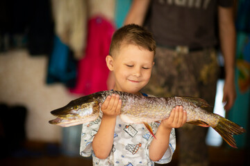 boy happy little fisherman with big hand pike