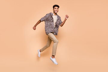 Fototapeta na wymiar Full size profile photo of brunet optimistic guy run jump wear modern shirt pants isolated on beige color background