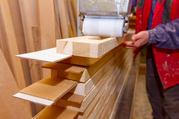 Carpenter smears the boards with hand roller tool, spreader for evenly application of glue on the wooden surface