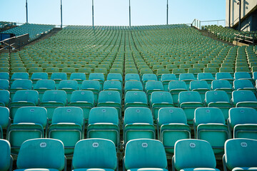 leeres Stadion im Freien bei sonnigem Wetter grüne Plastikstühle © Erika