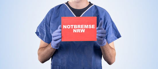 Arzt hält Schild mit aufschrift Notbremse NRW