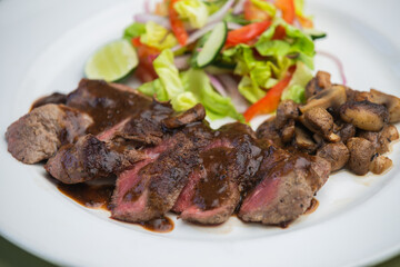Juicy beef tenderloin steak sliced on a plate with vegetable salad