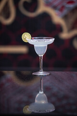 Classic margarita cocktail with lime on dark bar counter