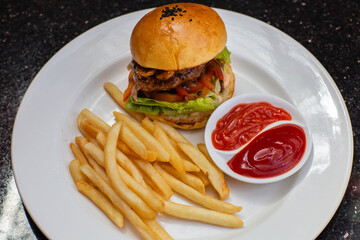 Delicious classic beef hamburger with french fries and ketchup on a plate