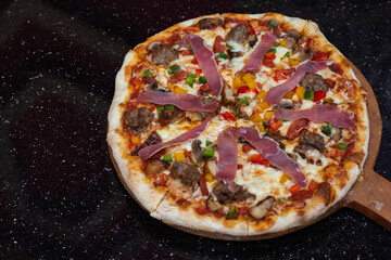 Close up of delicious sliced fresh pizza served on dark table