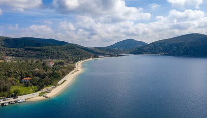 Panoramic top view on blue water sea coastline of Greek tourist island with green trees forest nature and white cloudy sky background