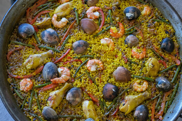Cooking traditional spanish mixed paella with seafood and chicken in large pot or pan
