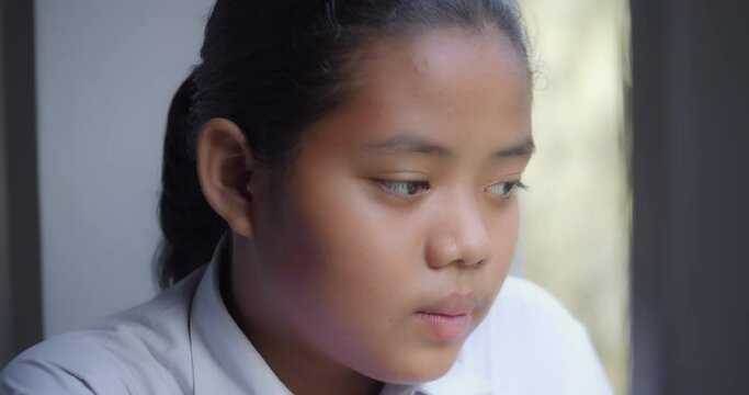 A native Asian black girl who started out as a teenage girl. There are pimples on her face and forehead and thinking, absent-minded, depressed, looked out of the window.