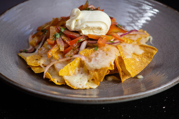 Plate of fresh nachos with a jalapeno, cheese and sauce. Traditional mexican appetizer snack