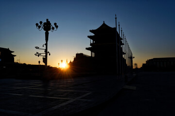 Shadows of buildings in tiananmen square with a blurry setting sun