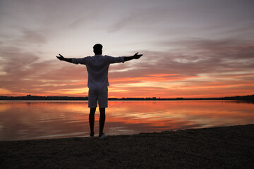 Man near river at sunset, back view. Nature healing power