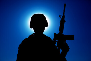 Silhouette of army soldier standing with service rifle in hand on background of night sky with...