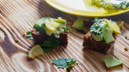 Prepare healthy sandwiches from grain rye bread spread with avocado paste with lemon and herbs