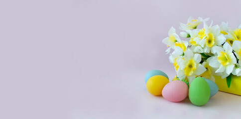 Happy Easter, Easter colored eggs in basket on pink background with spring flowers. Banner. An Easter card with copy of the place for the text