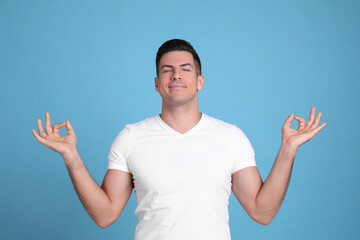 Man meditating on light blue background. Stress relief exercise