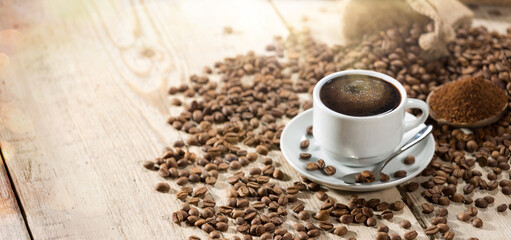 Coffee cup and coffee beans on a wooden table. Panoramic beverage background