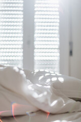 White bedding sheets and pillow in apartment at morning time with sunlight from windows