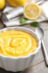 Delicious lemon curd in bowl on wooden table, closeup