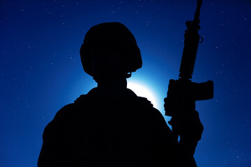 Night silhouette of army special operations forces soldier standing with service rifle on...