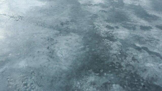 Frozen lake on a sunny day. Drone flying over the ice surface.