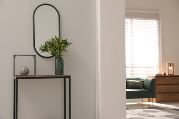 Console table with decor and mirror on light wall in hallway. Interior design