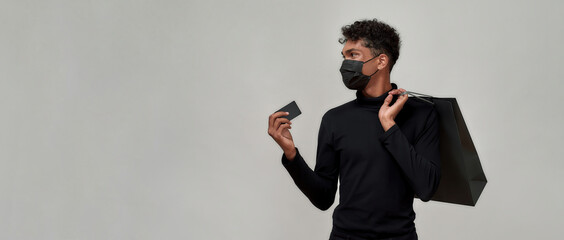 Young guy in protective mask holding plastic card