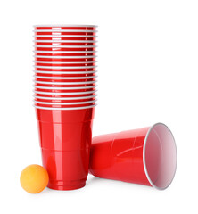 Red plastic cups and ball for beer pong on white background