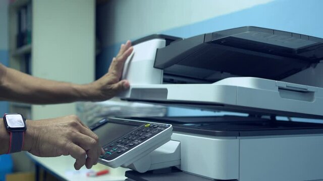 Male workers are working on documents by copying documents with a multifunction copier machine.