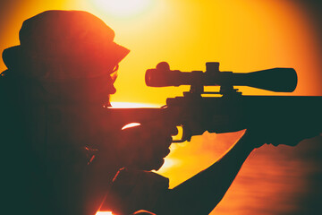Commando team sniper, army special forces shooter aiming, shooting sniper rifle while sitting on...