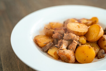 Potatoes with meat and mushrooms on a white plate