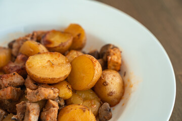 Potatoes with meat and mushrooms on a white plate