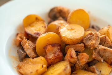 Potatoes with meat and mushrooms on a white plate