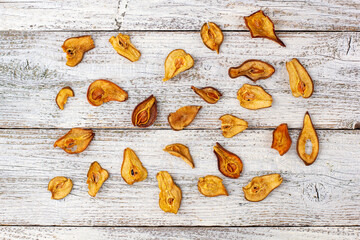 A pile of dried pears in slices on a white wooden background. Dried fruit chips. Healthy food