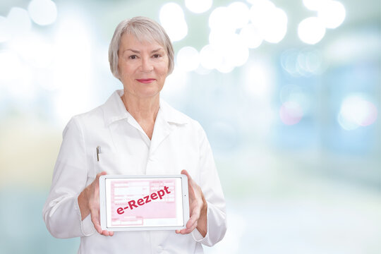 Smiling pharmacist showing a tablet computer with the german text: e-Rezept, meaning electronic prescription.