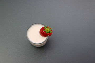 Pink milkshake with strawberries. Strawberry cocktail in a glass on a gray background. 
